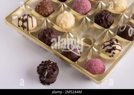 Fotografieren Sie viele Schokoladen in einem Paket eine Süßigkeit ist nicht in einem Paket auf weißem Hintergrund Stockfoto