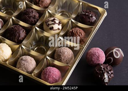 Fotoschokolade in verschiedenen Formen in einer Schachtel auf schwarzem Hintergrund Stockfoto