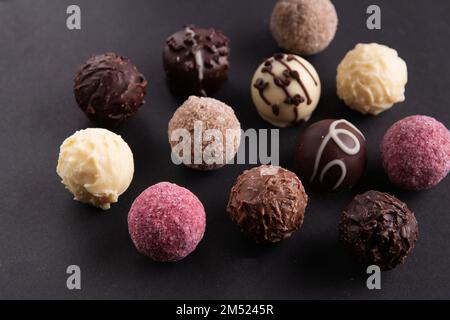 Foto mehrfarbige runde Schokoladenbonbons auf schwarzem Hintergrund Stockfoto