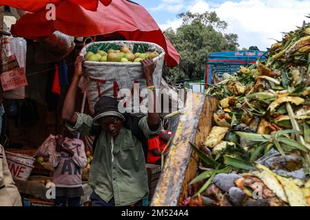 Nakuru, Kenia. 24. Dezember 2022. Ein Mann mit einem Korb voller Mangos läuft an einem Müllhaufen mit verdorbenem Obst und Gemüse vorbei, auf einem Großmarkt in Nakuru. Laut einem Bericht der Umweltschutzbehörde sind weggeworfene Lebensmittel für bis zu 8 Prozent der globalen Treibhausgasemissionen verantwortlich. (Foto: James Wakibia/SOPA Images/Sipa USA) Guthaben: SIPA USA/Alamy Live News Stockfoto