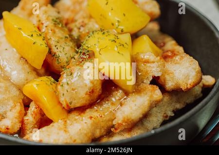Chinesisches Gericht mit süßem und saurem Schweinefleisch in schwarzer Schüssel Stockfoto