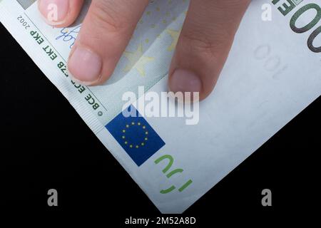 Hand mit 100 Euro Bargeld isoliert auf schwarzem Hintergrund Stockfoto