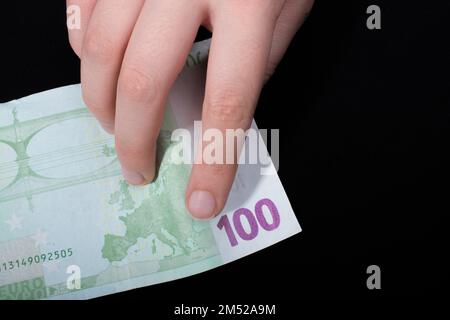 Hand mit 100 Euro Bargeld isoliert auf schwarzem Hintergrund Stockfoto