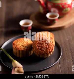 Chinesischer Mooncake zum Herbstfest, serviert mit Tee, auf einem Holztisch Stockfoto