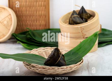 Zongzi oder Bakcang, traditionelles chinesisches Reisgericht aus Glutinreis gefüllt mit verschiedenen Füllungen und in Bambusblätter eingewickelt. Zubereitet von Stea Stockfoto