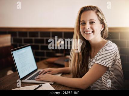 Ich bin bereit für das Finale. Abgeschnittenes Porträt einer glücklichen jungen Studentin, die ihren Laptop zum Lernen auf einem Tablet in einem Café nutzte. Stockfoto