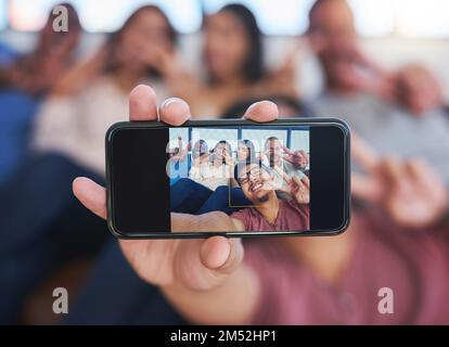 Sorgenfrei im Büro. Eine fröhliche Gruppe kreativer Kollegen, die gemeinsam im Büro für ein Selfie posieren. Stockfoto