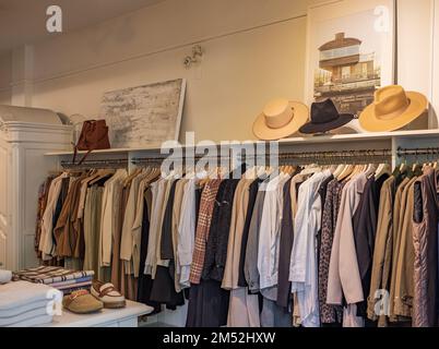 Modische Kleidung in einem Boutique-Laden. Ein Gestell mit stilvoller Kleidung neben einer Wand im Geschäft. Bekleidungsvertriebskonzept. Werbung, Verkauf, Mode. N Stockfoto