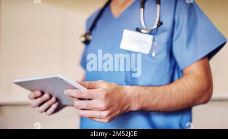 Bleiben Sie immer mit der medizinischen Gemeinschaft verbunden. Ein unerkannter Arzt, der sein Tablet in seiner Praxis benutzt. Stockfoto