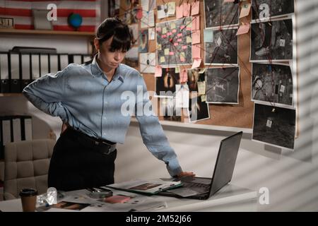 Eine Detektivin, die am Schreibtisch mit einem Laptop in ihrem Büro arbeitet Stockfoto