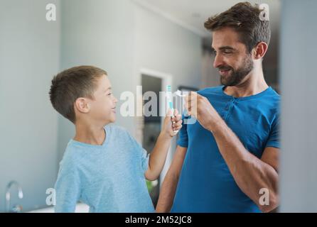 Bumm. Ein gutaussehender junger Mann und sein Sohn putzen sich im Bad die Zähne. Stockfoto