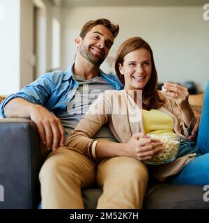 Ich genieße ihren Lieblingsfilm. Ein liebevolles junges Paar, das sich zu Hause einen Film auf dem Sofa ansieht. Stockfoto