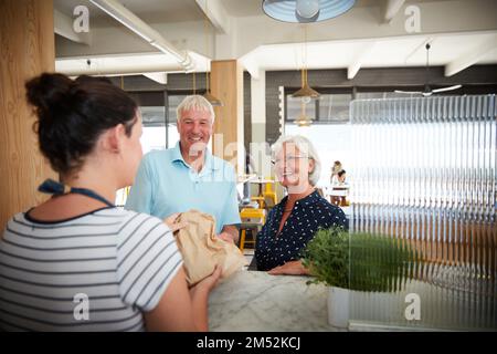 Wir holen unsere übliche Bestellung ab. Ein älteres Paar, das von einer Kellnerin bedient wird. Stockfoto