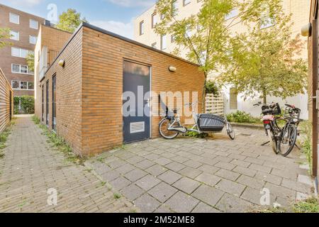 Ein Fahrrad, das vor einem Ziegelgebäude geparkt ist, wobei ein Fahrrad an der Seite des Gebäudes an die Wand lehnt Stockfoto