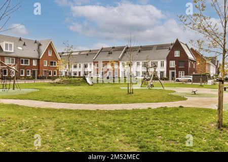 Einige Häuser befinden sich in der gleichen Nachbarschaft, eines ist aus rotem Ziegelstein und die anderen Gebäude sind weiß mit grauen Dächern Stockfoto