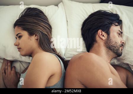 So nah, aber so weit auseinander. Ein gestrittenes Paar, das sich im Bett mit dem Rücken zugekehrt hat. Stockfoto