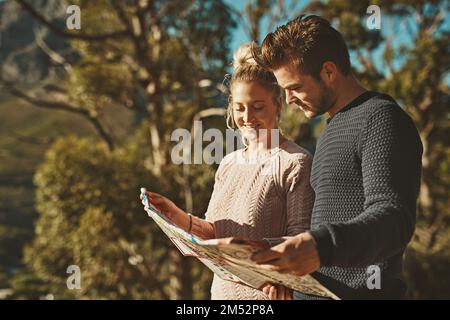 Wo wir hinfahren. Ein junges Paar, das beim Wandern auf eine Karte schaut. Stockfoto