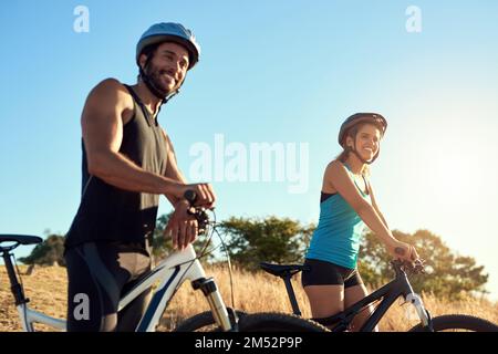 Mountainbike-Touren haben uns nur als Paar stärker gemacht. Ein glückliches junges Paar, das zusammen Mountainbike fährt. Stockfoto