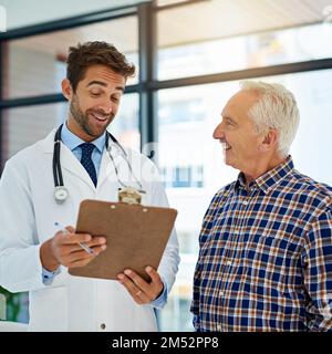 Wir hätten uns wirklich keine besseren Ergebnisse wünschen können. Ein fröhlicher Arzt, der gute Testergebnisse mit seinem reifen Patienten im Krankenhaus teilt. Stockfoto