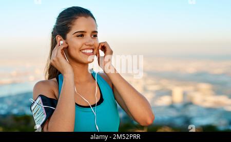 Musik sorgt dafür, dass Sie sich gut fühlen, wenn Sie sie wirklich brauchen. Eine junge Frau, die beim Laufen Musik hört. Stockfoto