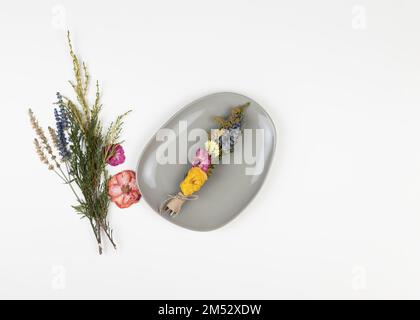 DIY-Fleck-Stick, um schlechte Energie zu verbannen. Getrocknete Kräuter und Blumen werden mit einem Faden in ein Bündel gebunden. Hausgemachter Räucherstäbchen für die mentale Praxis Stockfoto