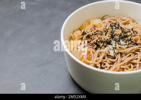 Koreanische Küche Naengmemilguksu, eine winterliche Delikatesse, wird dieses Buchweizen-Nudelgericht in einer kalten Hühnchen- oder Rinderbrühe serviert und mit einer kalten Scheibe garniert Stockfoto