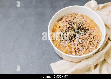 Koreanische Küche Naengmemilguksu, eine winterliche Delikatesse, wird dieses Buchweizen-Nudelgericht in einer kalten Hühnchen- oder Rinderbrühe serviert und mit einer kalten Scheibe garniert Stockfoto