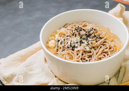 Koreanische Küche Naengmemilguksu, eine winterliche Delikatesse, wird dieses Buchweizen-Nudelgericht in einer kalten Hühnchen- oder Rinderbrühe serviert und mit einer kalten Scheibe garniert Stockfoto