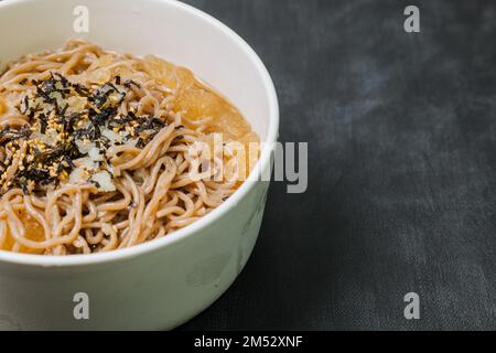 Koreanische Küche Naengmemilguksu, eine winterliche Delikatesse, wird dieses Buchweizen-Nudelgericht in einer kalten Hühnchen- oder Rinderbrühe serviert und mit einer kalten Scheibe garniert Stockfoto