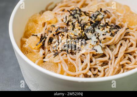 Koreanische Küche Naengmemilguksu, eine winterliche Delikatesse, wird dieses Buchweizen-Nudelgericht in einer kalten Hühnchen- oder Rinderbrühe serviert und mit einer kalten Scheibe garniert Stockfoto