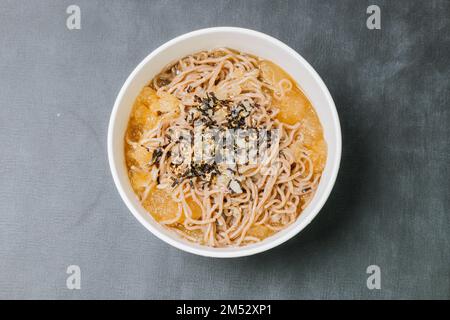 Koreanische Küche Naengmemilguksu, eine winterliche Delikatesse, wird dieses Buchweizen-Nudelgericht in einer kalten Hühnchen- oder Rinderbrühe serviert und mit einer kalten Scheibe garniert Stockfoto