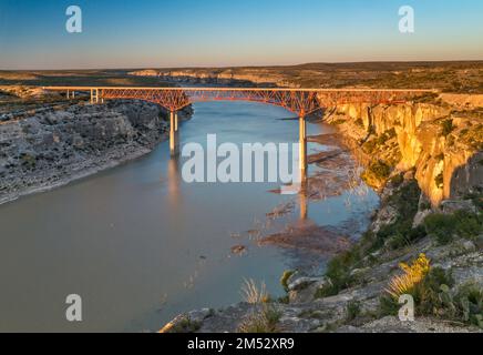 US-90 Highway Bridge, erbaut 1957, über dem Pecos River in der Nähe des Zusammenflusses Rio Grande, Kalksteinklippen, Sonnenuntergang, Texas, USA Stockfoto