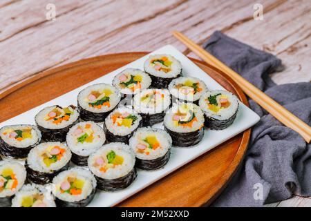 Reis mit Salz und Sesamöl gewürzt und in ein Blatt gerösteten gim (getrockneter Lava) mit Spinat, Karotten und eingelegtem weißem Rettich gerollt. Der lange Stockfoto