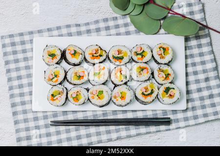 Reis mit Salz und Sesamöl gewürzt und in ein Blatt gerösteten gim (getrockneter Lava) mit Spinat, Karotten und eingelegtem weißem Rettich gerollt. Der lange Stockfoto