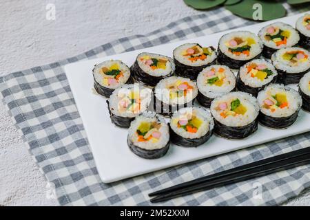 Reis mit Salz und Sesamöl gewürzt und in ein Blatt gerösteten gim (getrockneter Lava) mit Spinat, Karotten und eingelegtem weißem Rettich gerollt. Der lange Stockfoto