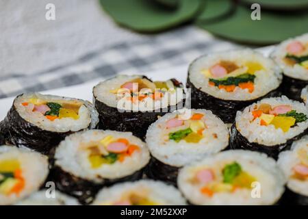 Reis mit Salz und Sesamöl gewürzt und in ein Blatt gerösteten gim (getrockneter Lava) mit Spinat, Karotten und eingelegtem weißem Rettich gerollt. Der lange Stockfoto
