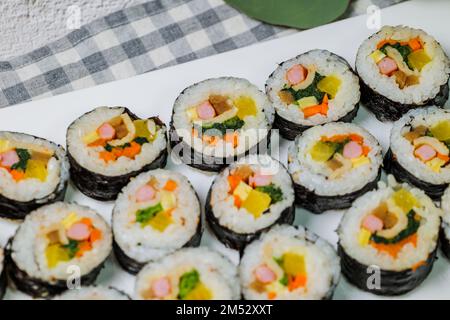 Reis mit Salz und Sesamöl gewürzt und in ein Blatt gerösteten gim (getrockneter Lava) mit Spinat, Karotten und eingelegtem weißem Rettich gerollt. Der lange Stockfoto
