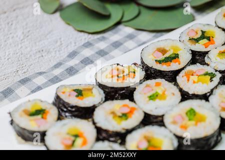 Reis mit Salz und Sesamöl gewürzt und in ein Blatt gerösteten gim (getrockneter Lava) mit Spinat, Karotten und eingelegtem weißem Rettich gerollt. Der lange Stockfoto