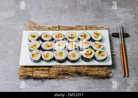 Reis mit Salz und Sesamöl gewürzt und in ein Blatt gerösteten gim (getrockneter Lava) mit Spinat, Karotten und eingelegtem weißem Rettich gerollt. Der lange Stockfoto
