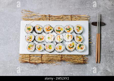 Reis mit Salz und Sesamöl gewürzt und in ein Blatt gerösteten gim (getrockneter Lava) mit Spinat, Karotten und eingelegtem weißem Rettich gerollt. Der lange Stockfoto