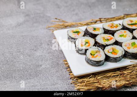 Reis mit Salz und Sesamöl gewürzt und in ein Blatt gerösteten gim (getrockneter Lava) mit Spinat, Karotten und eingelegtem weißem Rettich gerollt. Der lange Stockfoto