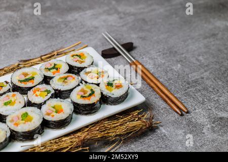 Reis mit Salz und Sesamöl gewürzt und in ein Blatt gerösteten gim (getrockneter Lava) mit Spinat, Karotten und eingelegtem weißem Rettich gerollt. Der lange Stockfoto