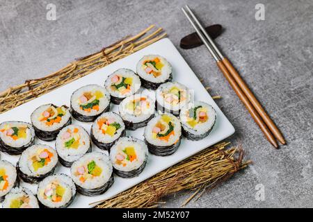 Reis mit Salz und Sesamöl gewürzt und in ein Blatt gerösteten gim (getrockneter Lava) mit Spinat, Karotten und eingelegtem weißem Rettich gerollt. Der lange Stockfoto