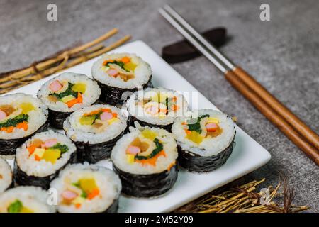 Reis mit Salz und Sesamöl gewürzt und in ein Blatt gerösteten gim (getrockneter Lava) mit Spinat, Karotten und eingelegtem weißem Rettich gerollt. Der lange Stockfoto