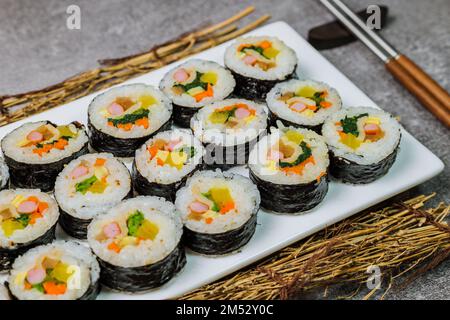 Reis mit Salz und Sesamöl gewürzt und in ein Blatt gerösteten gim (getrockneter Lava) mit Spinat, Karotten und eingelegtem weißem Rettich gerollt. Der lange Stockfoto