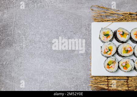 Reis mit Salz und Sesamöl gewürzt und in ein Blatt gerösteten gim (getrockneter Lava) mit Spinat, Karotten und eingelegtem weißem Rettich gerollt. Der lange Stockfoto