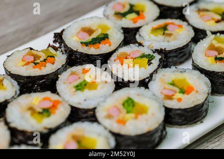Reis mit Salz und Sesamöl gewürzt und in ein Blatt gerösteten gim (getrockneter Lava) mit Spinat, Karotten und eingelegtem weißem Rettich gerollt. Der lange Stockfoto
