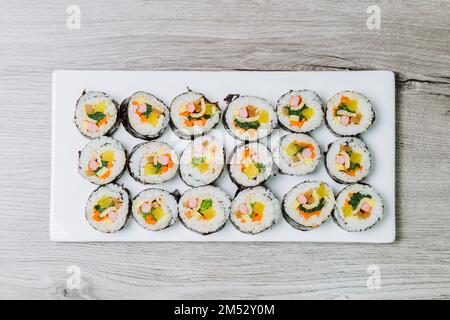 Reis mit Salz und Sesamöl gewürzt und in ein Blatt gerösteten gim (getrockneter Lava) mit Spinat, Karotten und eingelegtem weißem Rettich gerollt. Der lange Stockfoto