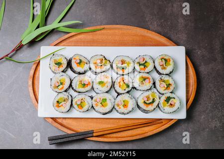 Reis mit Salz und Sesamöl gewürzt und in ein Blatt gerösteten gim (getrockneter Lava) mit Spinat, Karotten und eingelegtem weißem Rettich gerollt. Der lange Stockfoto