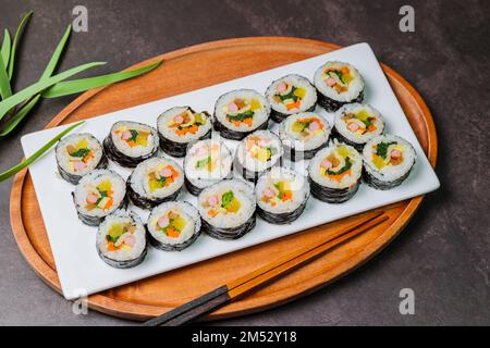 Reis mit Salz und Sesamöl gewürzt und in ein Blatt gerösteten gim (getrockneter Lava) mit Spinat, Karotten und eingelegtem weißem Rettich gerollt. Der lange Stockfoto